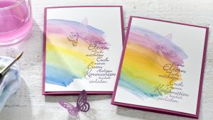 Ideen für Kommunion und Konfirmation: Über dem Regenbogen | Einladung mit aquarelliertem Regenbogen und ausgestanztem Schmetterling