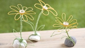 Ideen für Papierdraht: Dotterblumen | Blumen in Gelb mit einem Holzknopf als Blütenmitte auf einem Stein