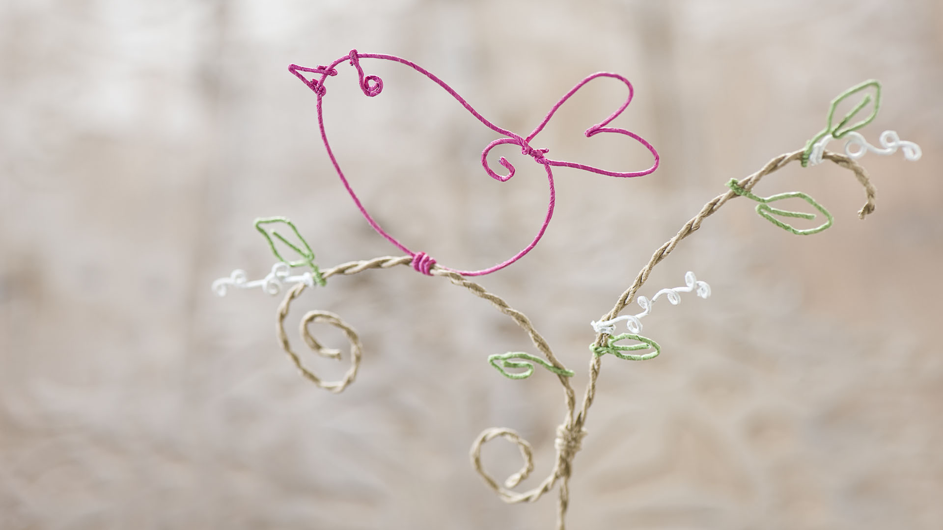 Ideen für Papierdraht: Vogelgezwitscher | Vogel aus Papierdraht in Pink auf Zweig mit grünen Blättern und weißen Blüten
