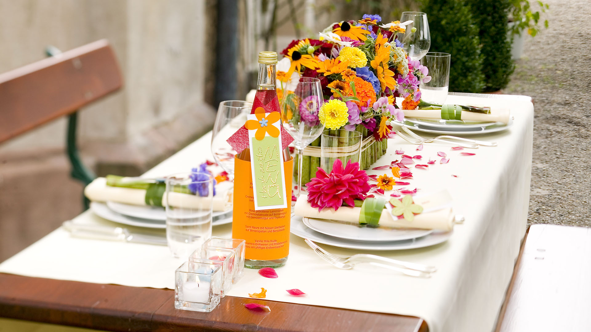 Ideen für Hochzeiten: Bunt wie das Leben | Hochzeitsmenü als Banderole mit Schriftzug und Blüte um eine Flasche Mineralwasser