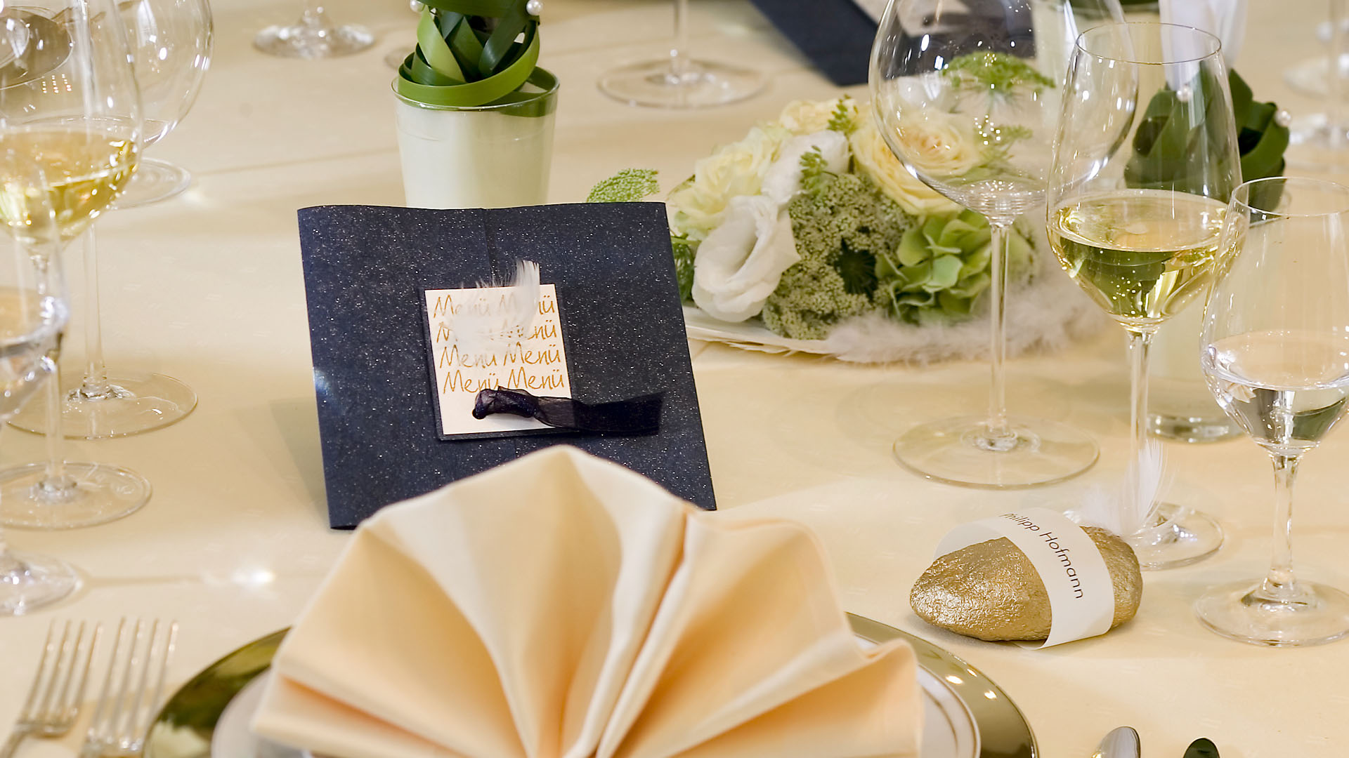 Ideen für Hochzeiten: Liebe federleicht | Menükarte in Dunkelblau, Champagner, Gold und Weiß mit einer dekorativen Feder