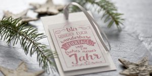 Ideen für die Weihnachtspost: Wir wünschen euch... | Schmucker Anhänger in Weiß, Grau und Rot mit Stempelmotiv im Handlettering-Stil