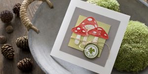 Ideen für Glückwünsche und Grußkarten: Glückspilze | Quadratische Karte in Weiß, Grau, Rot und Grün mit aquarellierten, ausdrucksstarken Glückspilzen und einem vierblättrigen Kleeblatt