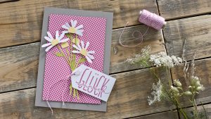 Ideen für Glückwünsche und Grußkarten: Blumen sagen mehr als 1000 Worte | Graue Glückwunschkarte mit einem kleinen, weiß-gelben Blumenstrauß aus Papier vor einem Karo-Hintergrund in Pink