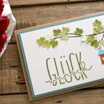 Ideen für Glückwünsche und Grußkarten: Glückwunsch | eine herzliche Papierszenerie in natürlichen Farben mit einem Ast mit Ahornblättern, einem Vogelhäuschen mit Herz und einem handgelettertem Schriftzug