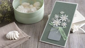 Ideen für Glückwünsche und Grußkarten: Blumengruß | handgemachte Karte in feinen und naütrlichen Farben. Auf dem salbeigrünem Hintergrund sind über einer grauen Vase mehrere weiße Blüten und zartgrüne Blätter arrangiert. An der Vase hängt ein Schild mit dem gestempelten Text: Alles Liebe.