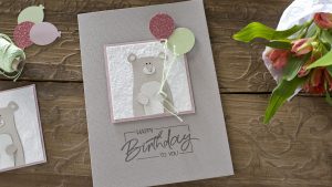 Ideen für Glückwünsche und Grußkarten: Zaubärhaft | selbstgemachte Geburtstagskarte mit einem trendigen Bären als Motiv, der aus verschiedenen Papieren ausgeschnitten wurde. Der Bär hält zwei Luftballons an einer Schnur in der Hand. Unter das liebevolle Motiv in zartem Grau, Wollweiß, Lindgrün und Rosé wurde der Text im Handlettering-Stil gestempelt: Happy Birthday to you.