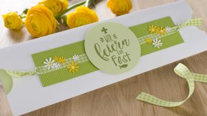 Ideen für Kommunion und Konfirmation: Blütenzauber | Ein ausgefallenes Etui als Einladungskarte in Weiß, Grün und Gelb mit vielen Blüten und einem gestempelten Text im Handlettering-Stil mit Kreuz und Fisch: Wir feiern ein Fest